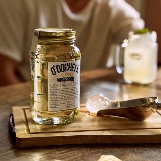 O'Donnell Moonshine vlierbessenlikeur in een Mason Jar, met daarachter een opgediende cocktail.