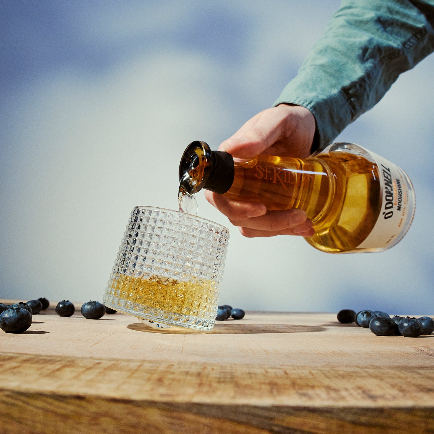 Tuimelglas omringd door bosbessen met whisky erin gegoten
