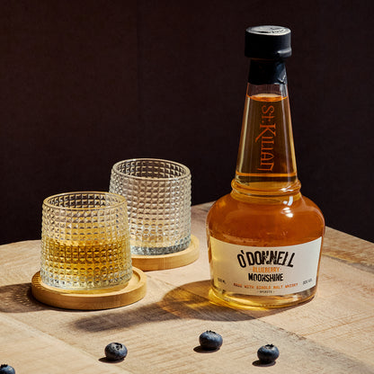 O'Donnell Blueberry Moonshine, O'Donnell en St.Kilian, hergestellt mit Single Malt Whisky naast een tumblerglas
