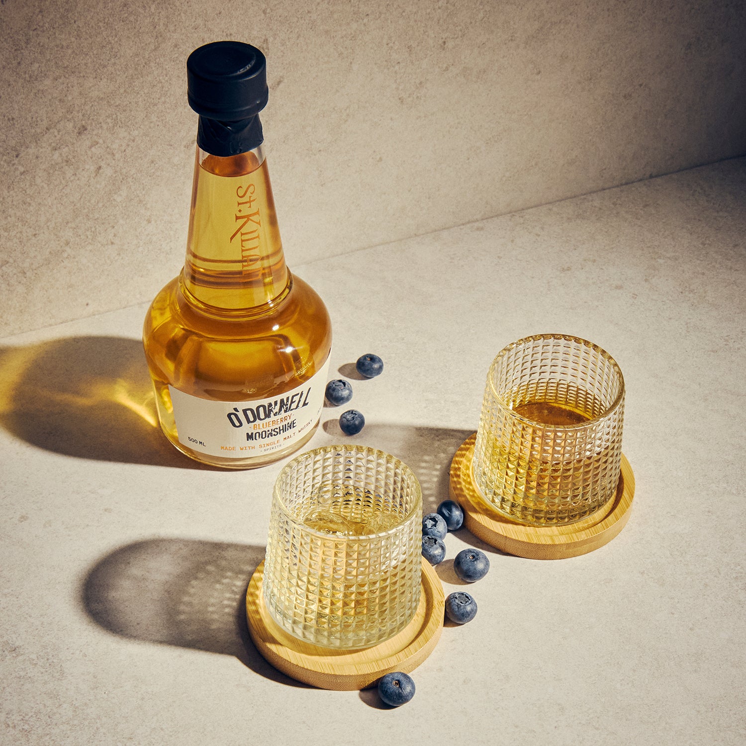O'Donnell Blueberry Moonshine, O'Donnell en St.Kilian, hergestellt mit Single Malt Whisky naast een tumblerglas
