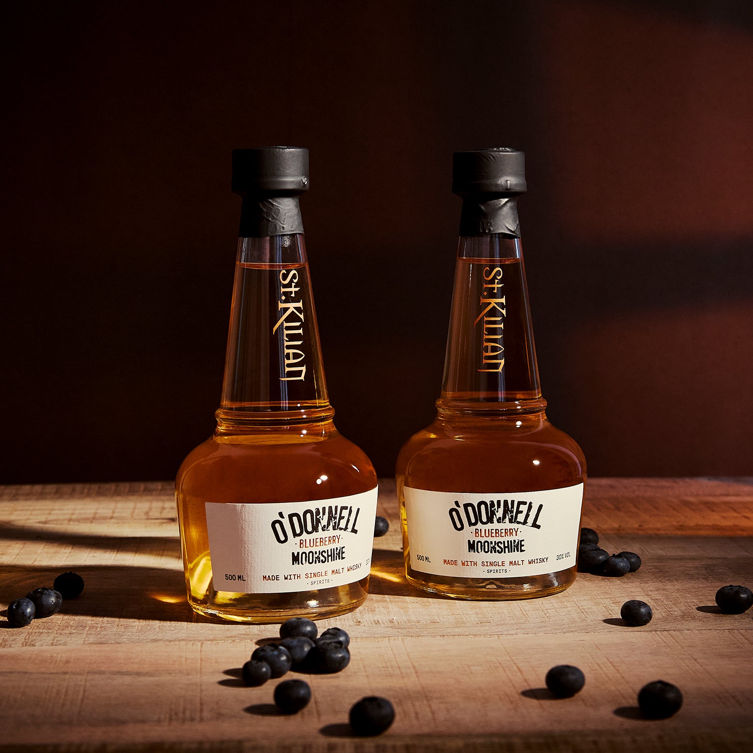 Twee O'Donnell bosbessen moonshine x whisky tegen een donkere achtergrond en omringd door bosbessen
