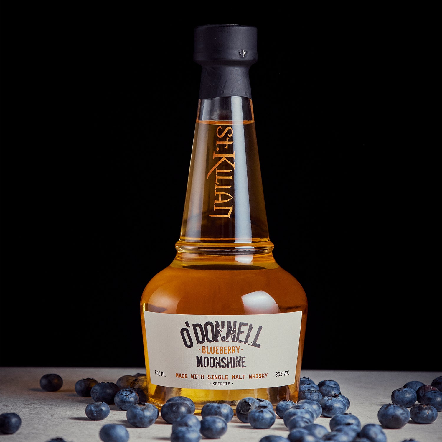 O'Donnell blueberry moonshine x whisky tegen een zwarte achtergrond en omringd door bosbessen