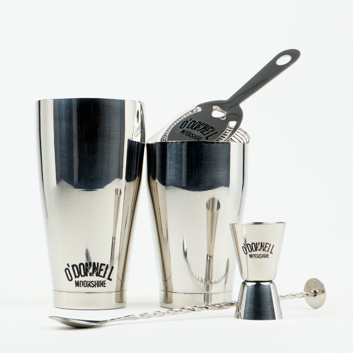 O'Donnell Moonshine-bar-set van roestvrij staal met Boston Shaker, barzeef, jigger en barllepel tegen een witte achtergrond.