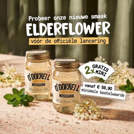 Twee kleine O'Donnell Moonshine vlierbloesem miniglazen staan te midden van witte vlierbloesem in het warme zonlicht.