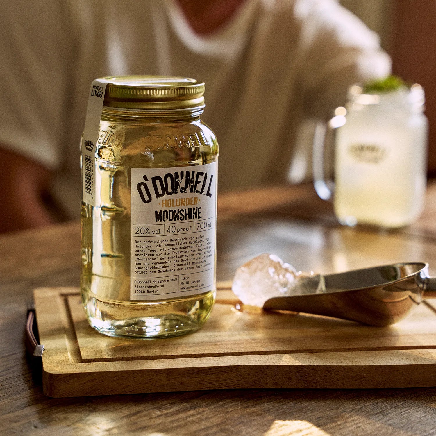 O'Donnell Moonshine  vlierbessenlikeur in een Mason Jar, met daarachter een opgediende cocktail.